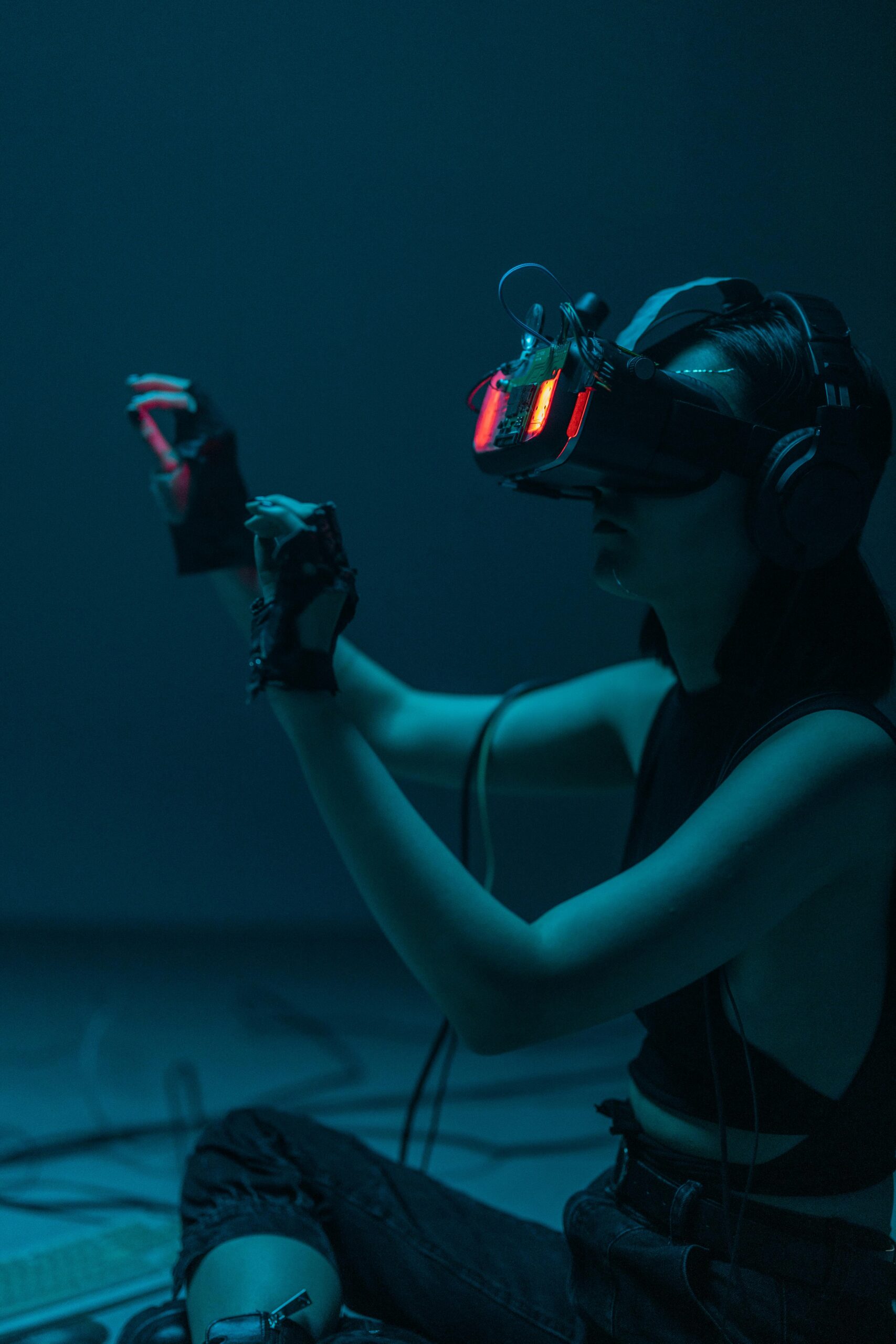 A person immersed in a virtual reality experience with neon-lit VR gear in a moody studio setting.